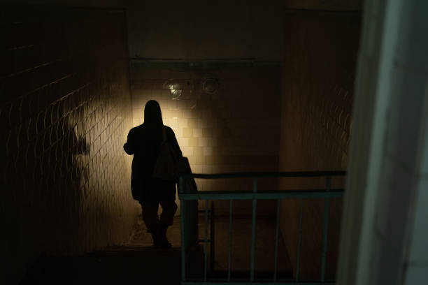 istock Rear view of a man walking in corridor of the building using flashlight. Nuclear post-apocalypse survivors 1448121890
