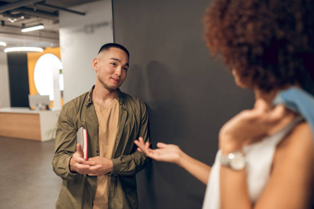 istock Corporate employee conversing with a coworker in the corridor 1448121916