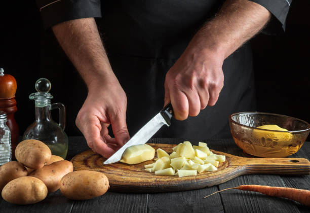 istock The chef cuts raw potatoes into pieces with a knife before preparing breakfast or dinner. Close-up of a cook hands while working in a restaurant kitchen. 1448123232