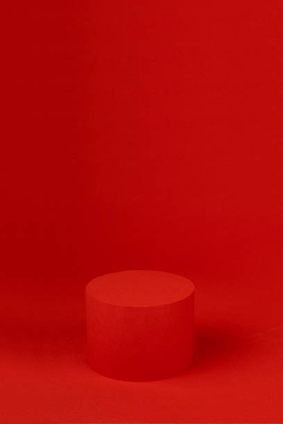 istock Red cylinder podium mockup on table on rich saturated background for presentation cosmetic products, gifts, goods in minimal modern style, copy space, vertical. Template for advertising, design. 1448124160