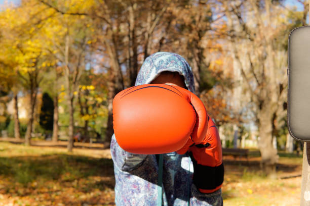 unrecognizable female boxer strikes with red boxing globes. Sportswoman making sport with power female boxer strikes with red boxing globes. Sportswoman training outside boxercise stock pictures, royalty-free photos & images