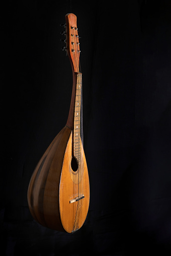 Mandolin placed vertically on a black background. Back view.