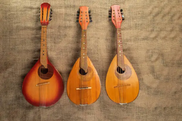 Three old mandolins on a background of rough burlap texture.