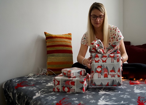 Young happy woman wrapping present at home for Christmas and New Year