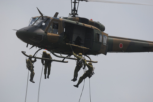 A couple of US Military Bell AH-1 Cobra helicopters patrolling low over ocean waters on a sunny day in Okinawa, Japan