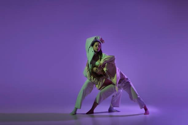istock Dance performance. Stylish female dancers at contemporary choreography dance class isolated over crystal purple background. Style, youth, music and fashion 1448140472
