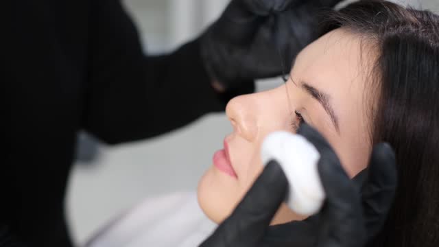 A young beautiful woman undergoes the procedure of eyebrow correction in a beauty salon