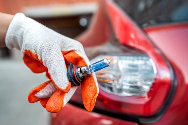 istock Car service men holding halogen h7 lamp for change in headlight 1448147126