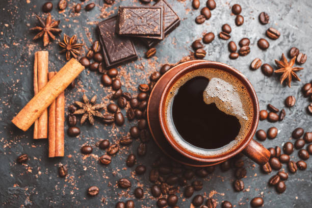 istock Fresh brewed black coffee in a cup on dark background with coffee beans and chocolate pieces, top view 1448150222
