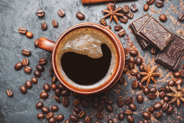 istock Fresh brewed black coffee in a cup on dark background with coffee beans and chocolate pieces, top view 1448150771