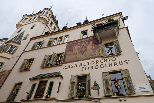 Bolzano, Italy - November 1, 2022: The Torgglhaus (Home to the winepress) is a historic building in Bolzano, built in 1913 to a design by the architect Albert Netzer. Outside are two murals: one depicts a German knight, the second depicts the biblical spies Joshua and Caleb returning home with a huge bunch of grapes