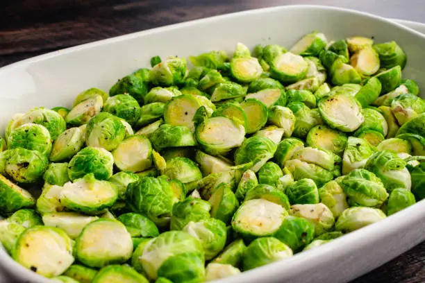 A baking dish full of raw Brussels sprouts cut in half and tossed in olive oil, salt and pepper