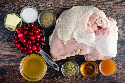 Overhead view of raw turkey breast, fresh cranberries, and other ingredients