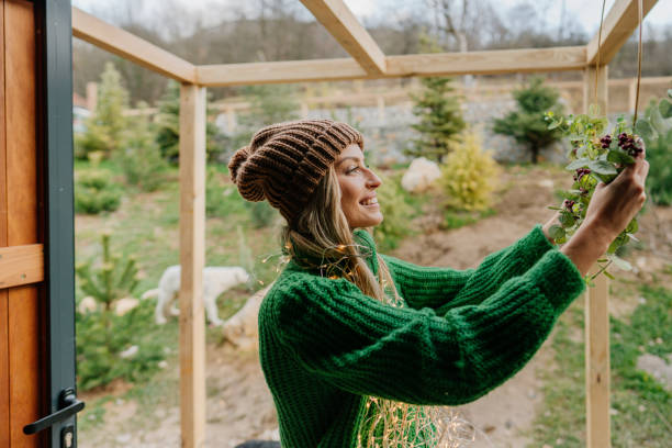 Photo of a young woman putting up Christmas decorations, attaching a wreath, and preparing for the upcoming holiday season.