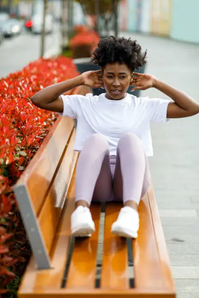 Photo of A Woman of African-American Ethnicity is Training on a Park Bench.