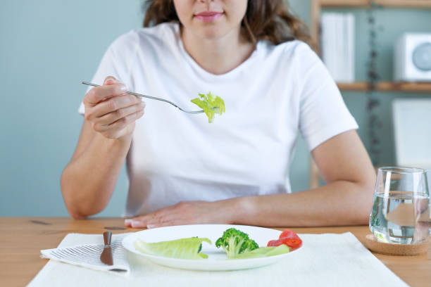 istock Dieting problems. Eating disorder. Young woman eating lettuce 1448161260
