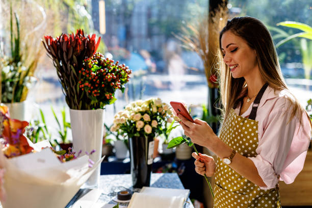 istock A young beautiful woman is using a phone for text messaging in a flower shop. 1448162893