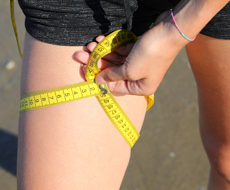 measurement of the circumference of the leg of girl with  tape measure and measures in centimeters