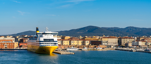 Livorno, Italy - 1 December, 2022: large passenger ferry in the port of Livorno with the old town and waterfront behind