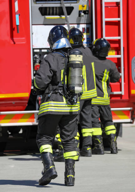 酸素タンクと消防車を背景にした消防士 - 戦隊 ストックフォトと画像