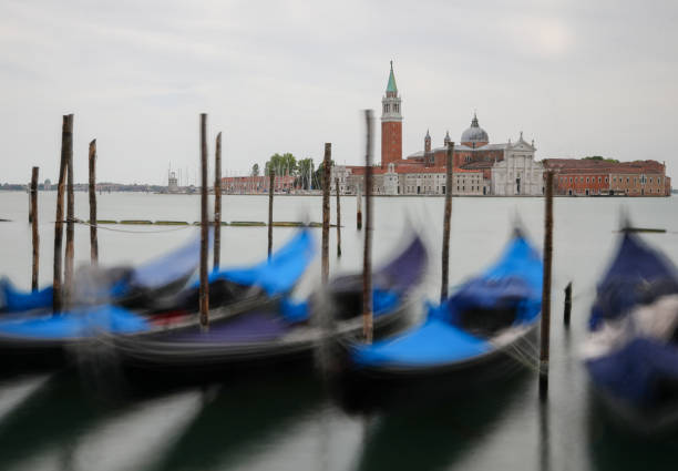 Church of Saint George in Venice in Italy and Gondolas Boat Church of Saint George in Venice in Italy and moved gondolas moving on the water san giorgio maggiore stock pictures, royalty-free photos & images