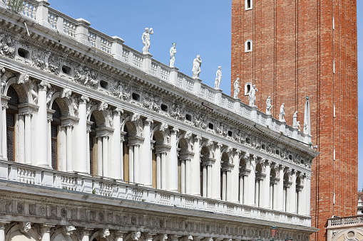 facade of the historic building called BIBLIOTECA MARCIANA in Venice in Italy and the bell tower of St. Mark