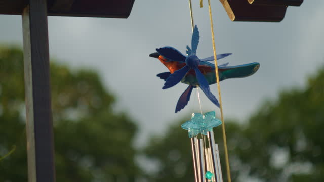 Ornamental Blue Bird and wind chimes hang from garden trellis