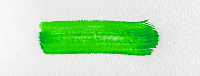 Green paint stroke on a white textured paper.