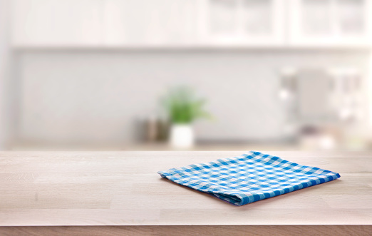 Blue folded kitchen napkin on wooden table. Towel on tabletop. Food advertisement design backdrop. Product display.