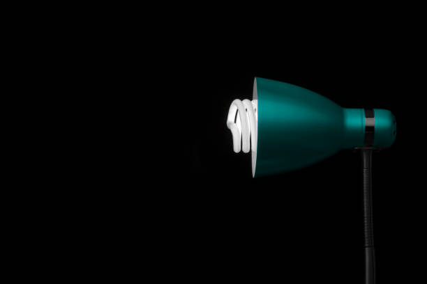 Detail of blue desk lamp on black background, with light bulb. Copy space. Horizontal orientation. No people.