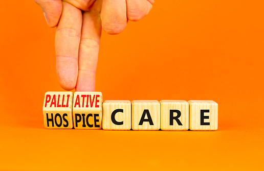 Palliative or hospice care symbol. Concept word Palliative care Hospice care on wooden cubes. Doctor hand. Beautiful orange background. Medical palliative or hospice care concept. Copy space.