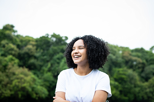Environmental portrait of a beautiful young black woman smiling in a park