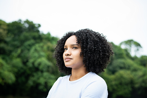 Environmental portrait of a thoughtful beautiful young black woman looking away in a park