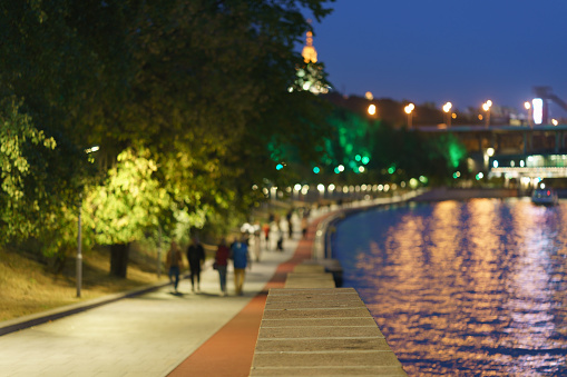 Defocused photography. Selective focus. People go for a walk on the Moscva river embankment in the Moscow public park.