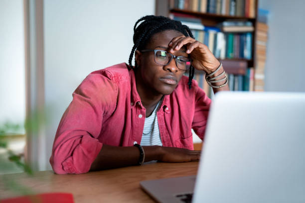 istock Bored unhappy young African man freelance worker looking at laptop screen cannot concentrate on work 1448189626