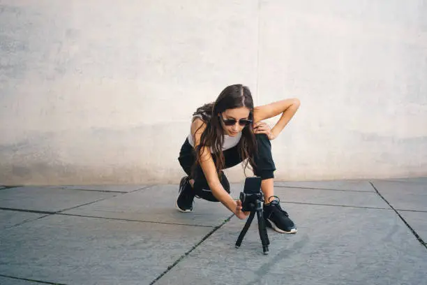 Photo of Young influencer filming a dance video for social media with a smartphone
