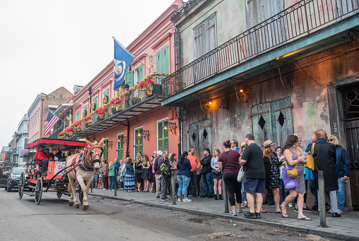 New Orleans, United States of America  December 4, 2022. View of St Peter street in New Orleans, with people queuing in front of the Preservation Hall jazz venue and a mule-drawn carriage in the street.