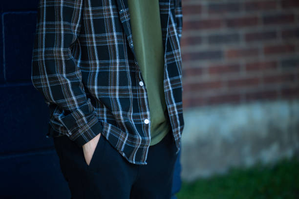 un anónimo cualquier hombre de pie contra una pared de ladrillos con las manos en los bolsillos con espacio de copia - lumberjack shirt fotografías e imágenes de stock