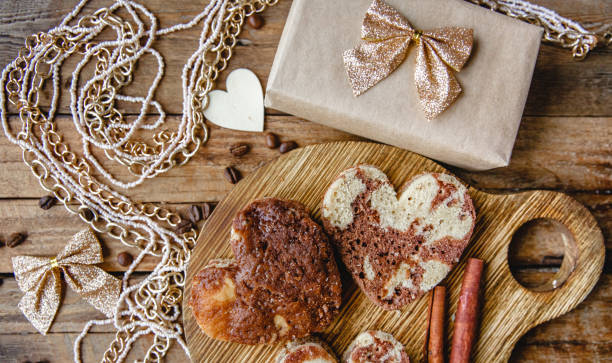 istock Heart-shaped pastries on a round wooden board, an openwork tablecloth, a craft gift box, golden bows, beads and cinnamon on a wooden table.  Flat layout for Valentine's Day 1448196658