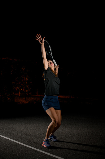 athletic woman tennis player on bent knees and with arms raised up is preparing to hit the tennis ball