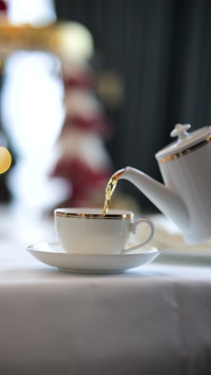 Pouring tea into a glass with a teapot on New Year's Day, drinking Christmas tea, Christmas decorated table and tea