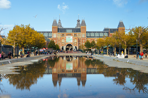 Amsterdam - 02 October 2022 - Famous Rijksmuseum in Amsterdam, Netherlands. There are a lot of tourists. Reflection on the autumn water.