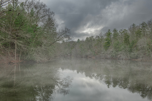 Glassy water at Byrd Creek lake in Cumberland State Park Tennessee during a cold, rainy day, providing a beautiful setting for nature scenes.