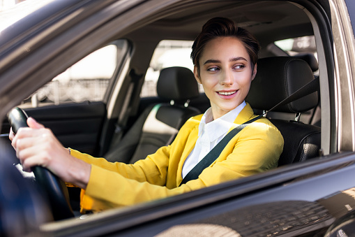 Beautiful young woman with short hair driving car in the city - Pretty caucasian female adult business woman wearing elegant suit going to work in the office