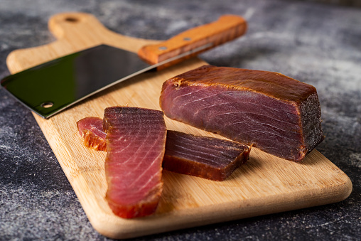 Piece of tuna mojama or cecina cut into slices on a cutting board.