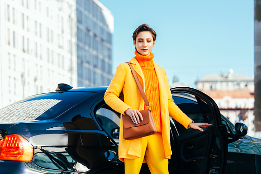 Beautiful young woman with short hair driving car in the city - Pretty caucasian female adult business woman wearing elegant suit going to work in the office