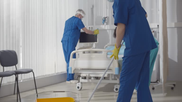 Janitors in scrubs and safety mask cleaning hospital room