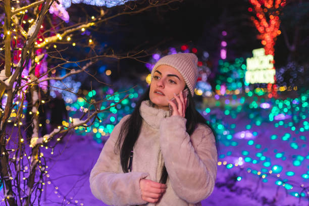 istock Young woman talking on the phone while surrounded by Christmas lights 1448213945
