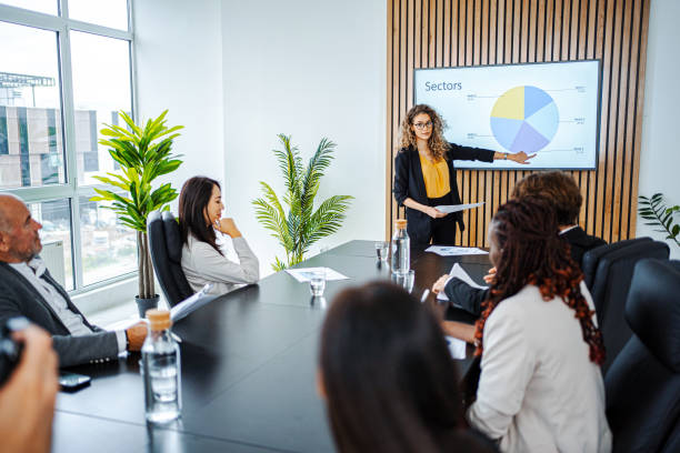 empresaria liderando reunión de negocios utilizando gráfico de estadísticas en presentación tv - presentation fotografías e imágenes de stock