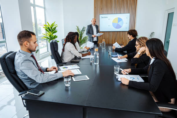 istock Experienced businessman leading business meeting using statistics chart on presentation TV 1448216941